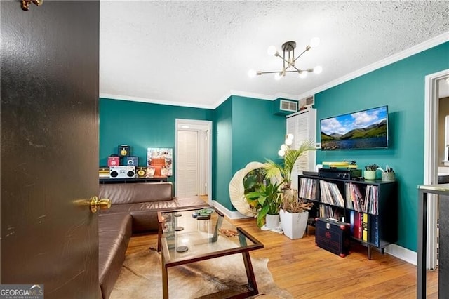 sitting room featuring baseboards, wood finished floors, an inviting chandelier, crown molding, and a textured ceiling