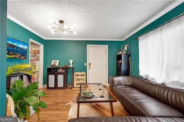 living area featuring a textured ceiling, ornamental molding, wood finished floors, and an inviting chandelier