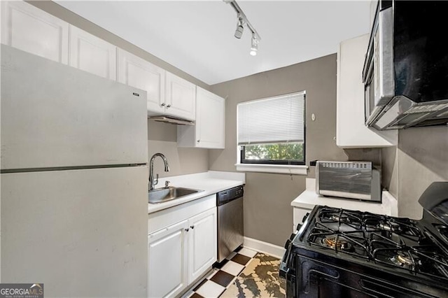 kitchen with a sink, white cabinetry, light countertops, appliances with stainless steel finishes, and light floors