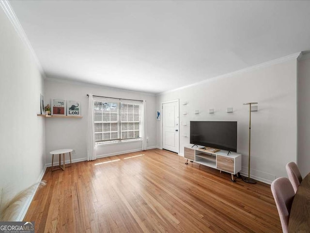 unfurnished living room featuring crown molding, baseboards, and wood finished floors