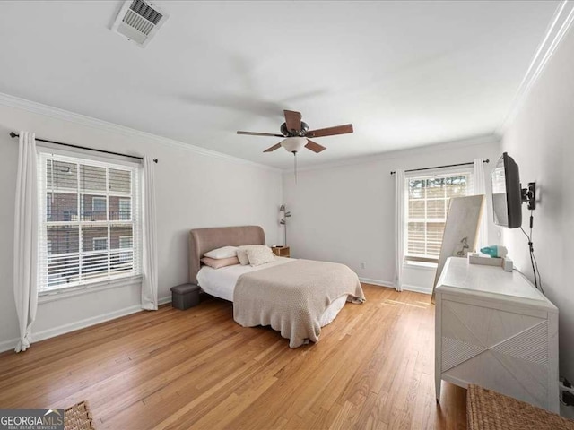 bedroom with a ceiling fan, baseboards, visible vents, light wood finished floors, and crown molding