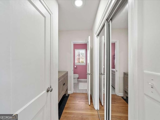 corridor featuring light wood-type flooring and baseboards