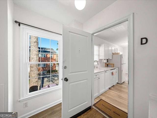 entryway with light wood-style flooring, baseboards, and a sink