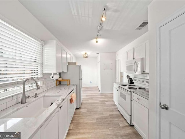 kitchen featuring white appliances, light stone counters, light wood-type flooring, white cabinetry, and a sink