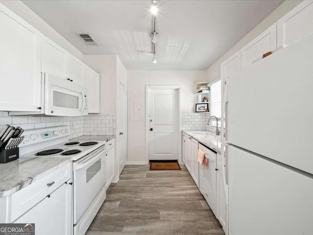 kitchen featuring light stone counters, visible vents, white cabinets, a sink, and white appliances