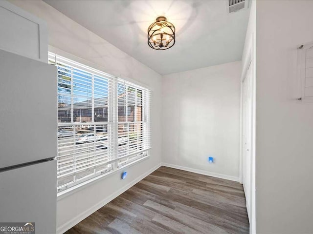 empty room featuring baseboards, visible vents, and wood finished floors