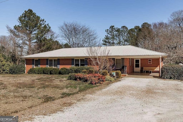 ranch-style home featuring driveway, brick siding, and a front lawn