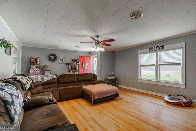 living room with baseboards, wood finished floors, visible vents, and crown molding