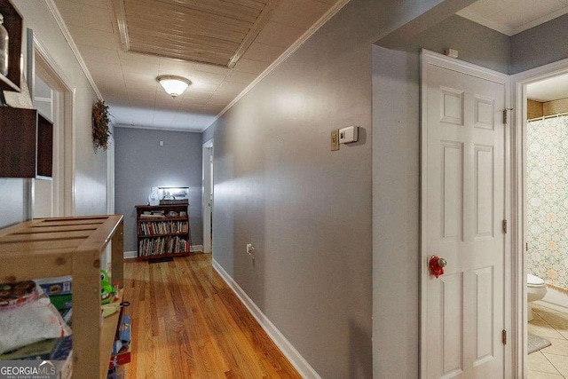 hall featuring ornamental molding, light wood-type flooring, and baseboards