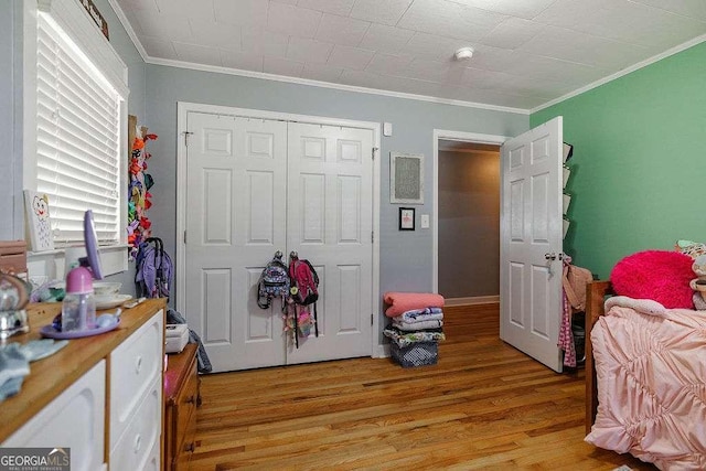 bedroom featuring light wood-style flooring, ornamental molding, and a closet