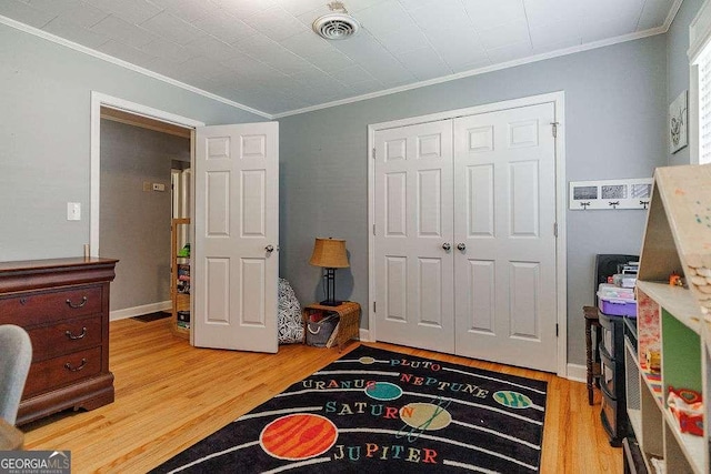 bedroom featuring light wood-style floors, a closet, visible vents, and ornamental molding