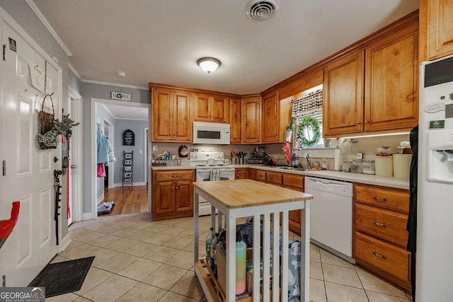 kitchen featuring light tile patterned floors, white appliances, ornamental molding, and brown cabinets