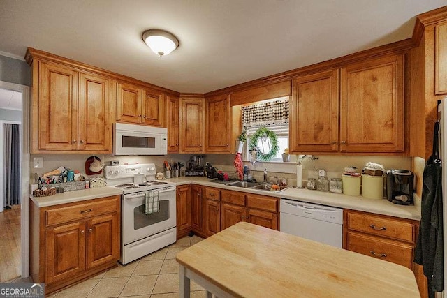 kitchen featuring brown cabinets, white appliances, light countertops, and a sink