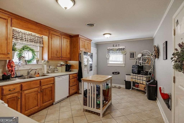 kitchen with white appliances, a sink, visible vents, light countertops, and ornamental molding