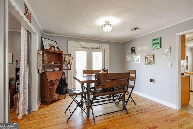 dining room featuring light wood finished floors, visible vents, ornamental molding, and french doors