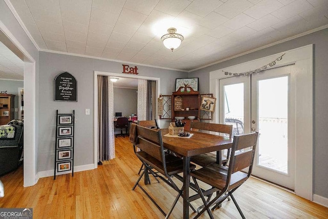 dining space featuring ornamental molding, light wood-type flooring, french doors, and baseboards