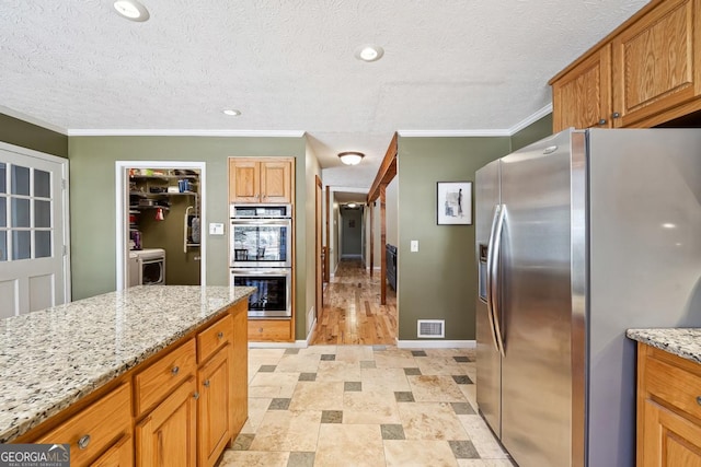 kitchen featuring a textured ceiling, light stone counters, visible vents, baseboards, and appliances with stainless steel finishes