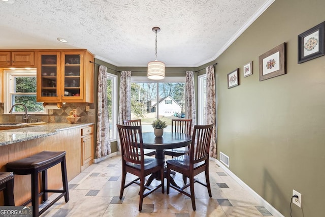 dining room featuring a wealth of natural light, stone tile floors, visible vents, and baseboards