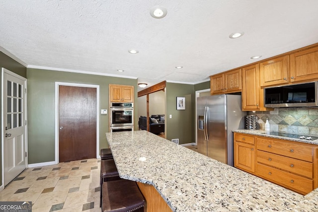 kitchen with a breakfast bar area, decorative backsplash, appliances with stainless steel finishes, light stone countertops, and baseboards