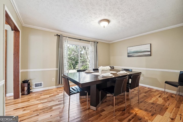 dining area with baseboards, crown molding, visible vents, and wood finished floors