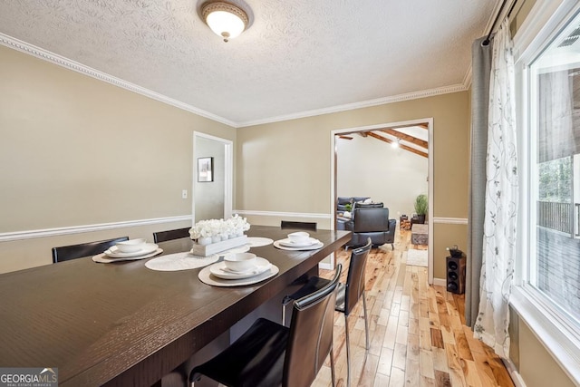 dining area featuring light wood finished floors, crown molding, and a textured ceiling