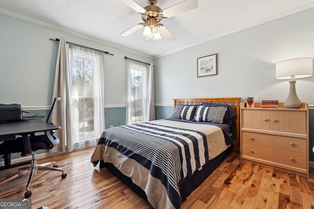 bedroom featuring a textured ceiling, ornamental molding, and light wood-style floors