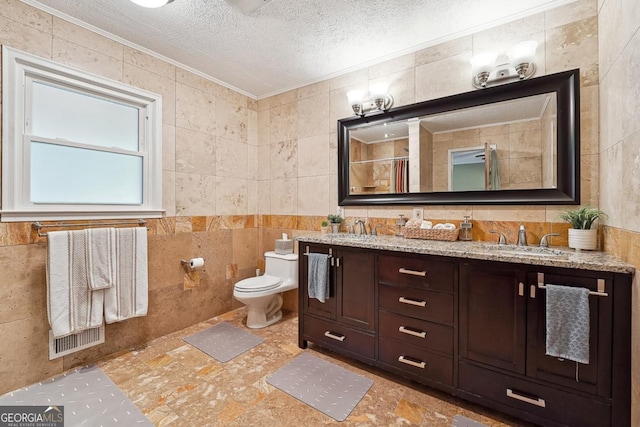 bathroom featuring crown molding, tile walls, double vanity, a sink, and a textured ceiling