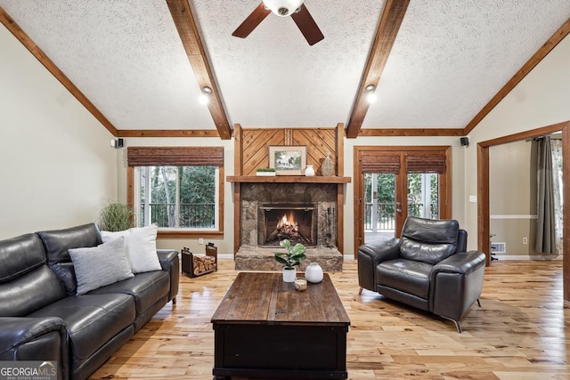 living room featuring vaulted ceiling with beams, light wood finished floors, and a fireplace