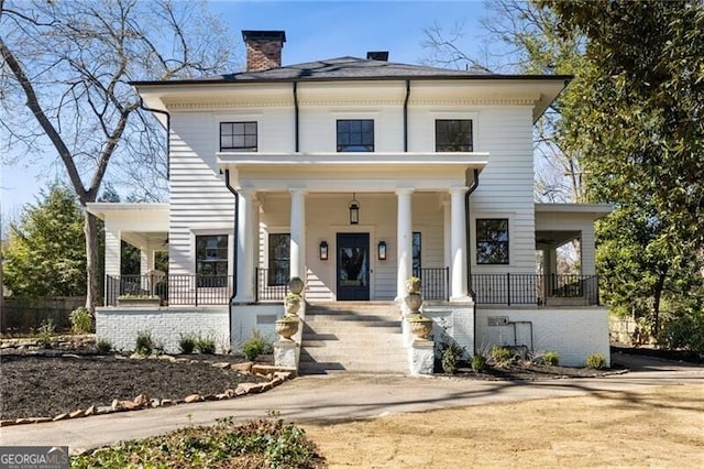 view of front facade featuring covered porch and a chimney