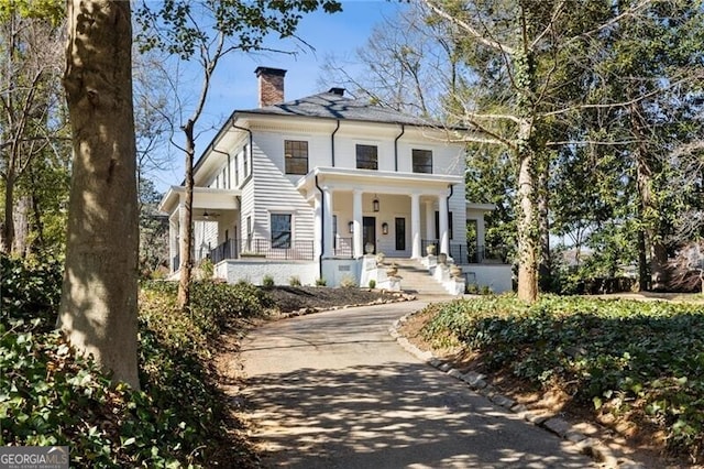 view of front of property with covered porch, driveway, and a chimney