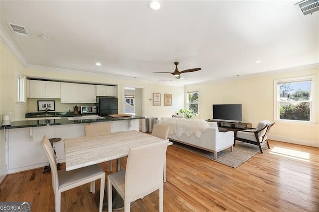 dining space featuring light wood finished floors, visible vents, and crown molding