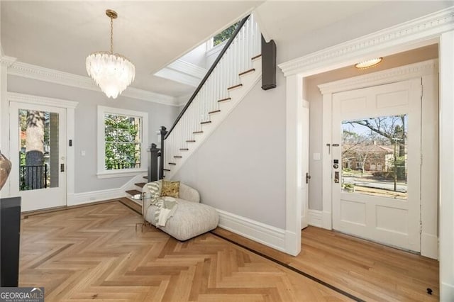 entrance foyer featuring a notable chandelier, crown molding, stairway, and baseboards