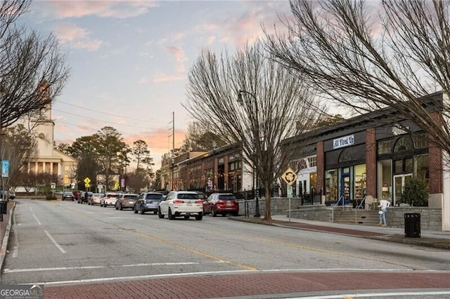 view of road featuring curbs, street lighting, traffic signs, and sidewalks