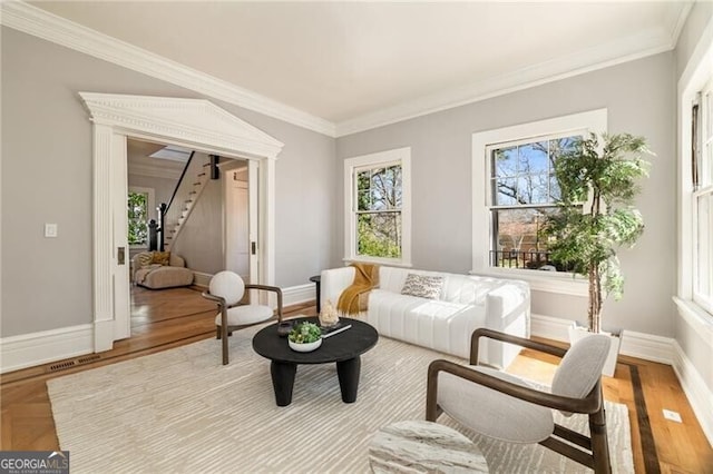 sitting room featuring ornamental molding, plenty of natural light, baseboards, and stairs