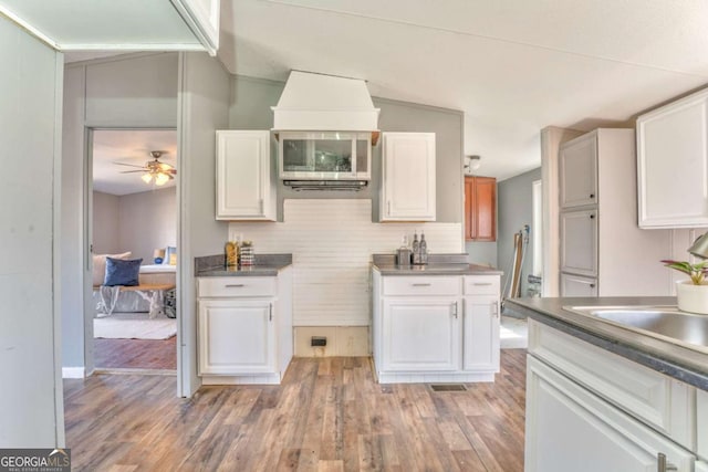 kitchen with dark countertops, light wood-style floors, white cabinetry, and a ceiling fan