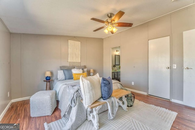 bedroom with ceiling fan, baseboards, wood finished floors, and ensuite bathroom