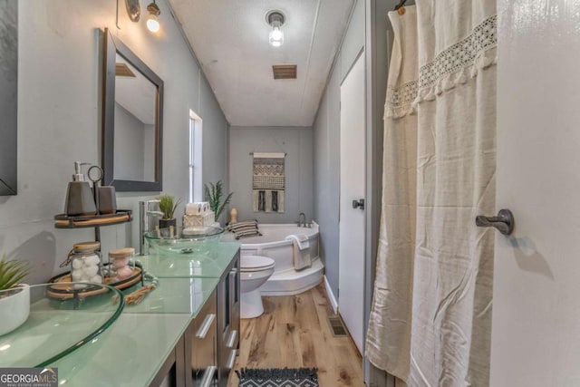 bathroom featuring a tub to relax in, visible vents, toilet, wood finished floors, and vanity