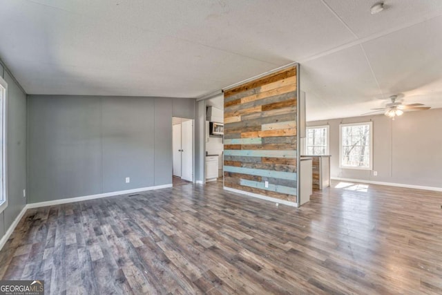 unfurnished living room with a ceiling fan, baseboards, and wood finished floors