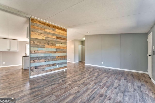 unfurnished living room with baseboards and dark wood-type flooring