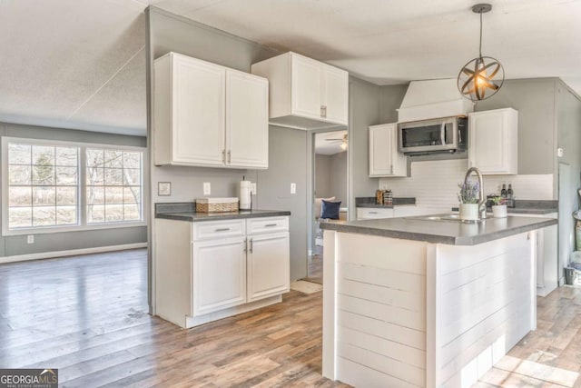 kitchen featuring stainless steel microwave, dark countertops, and white cabinets