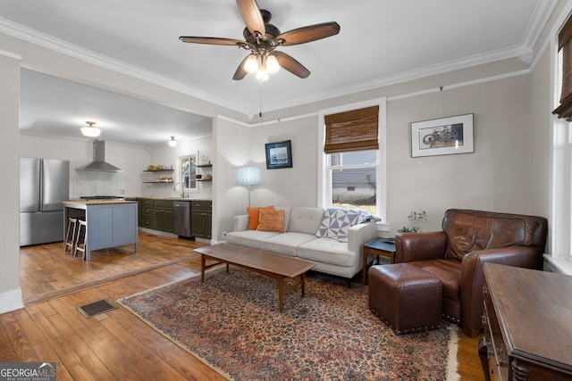 living area with light wood-style floors, visible vents, crown molding, and ceiling fan