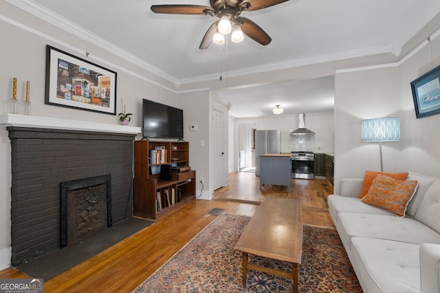 living room with visible vents, a ceiling fan, wood finished floors, crown molding, and a fireplace