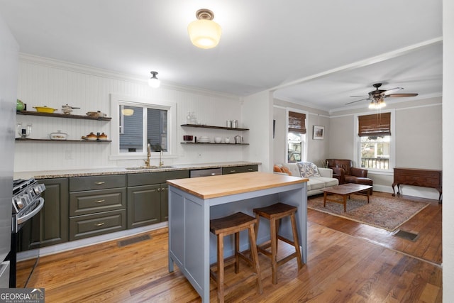 kitchen featuring butcher block countertops, a sink, light wood-style floors, open shelves, and gas range oven