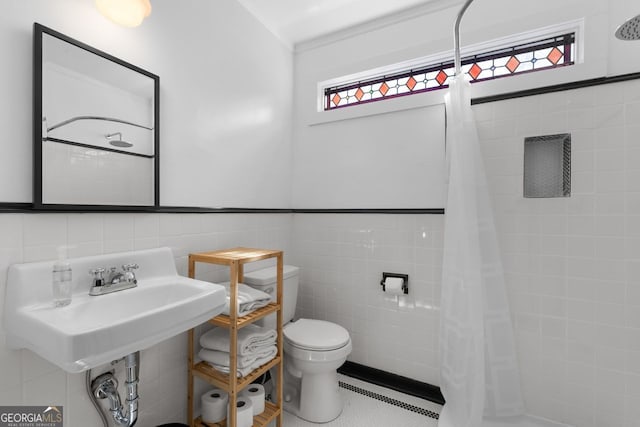 full bathroom featuring toilet, tiled shower, baseboard heating, and tile walls