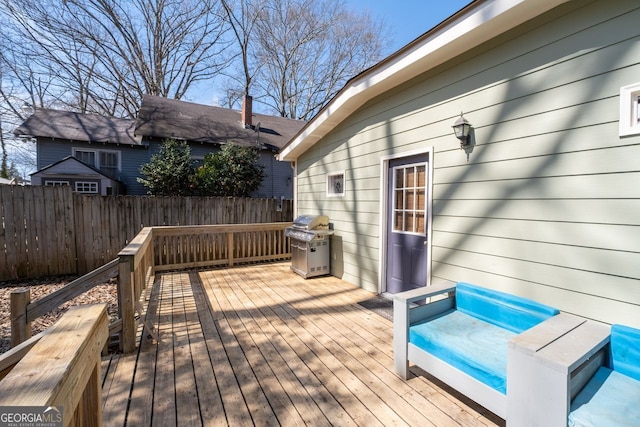 wooden deck featuring fence and a grill