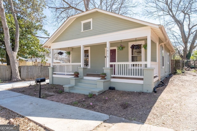 bungalow-style home with covered porch and fence