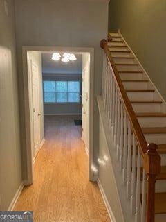 hall with stairs, baseboards, and wood finished floors