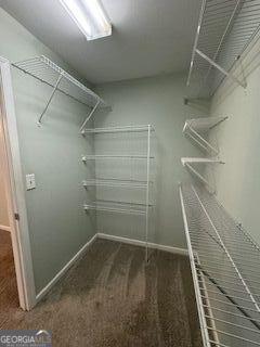 walk in closet featuring dark carpet