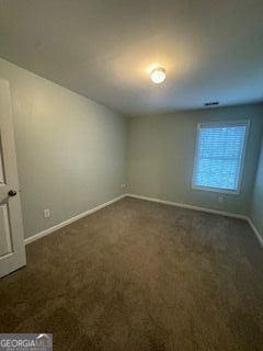 interior space featuring dark colored carpet and baseboards