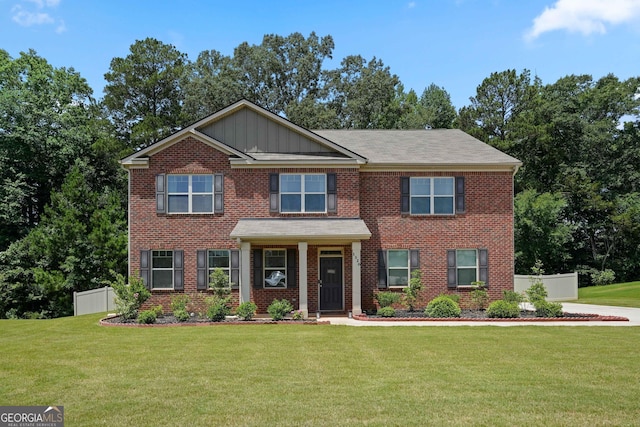 view of front of house with fence, a front lawn, board and batten siding, and brick siding